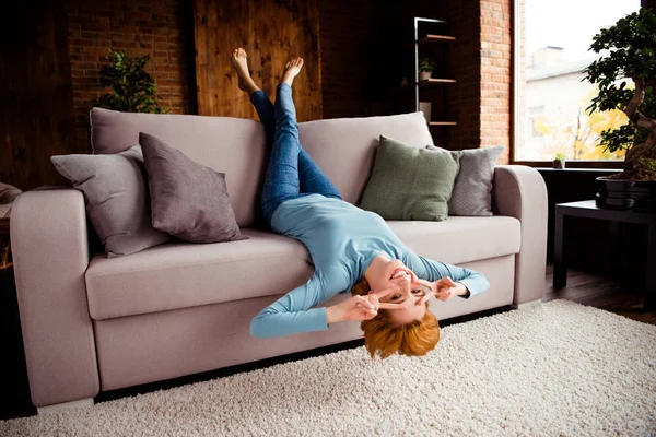 Full length body size photo beautiful she her lady hands arms legs raised upside down show v-sign eyes best day wear blue casual pullover jeans denim sit comfy couch divan house living room indoors — Stock Photo, Image