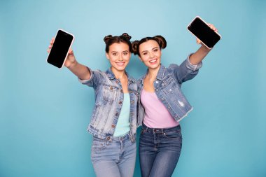 Portrait of cute attractive teenagers teens addicted to modern technology holding hands have strolls show gadgets give feedback recommend advise isolated azure background dressed denim clothes clipart