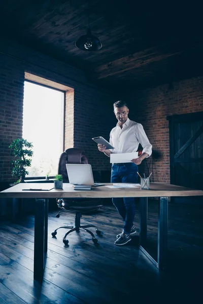 Svislá plná délka velikost těla fotografie krásný on ho jeho chlapák pozorný pohled na statistiku drží e-knihu e-Reader hodinek Webinar Kontrola čísla notebook stůl stojánek nosit specifikace formální nosit bílá košile — Stock fotografie