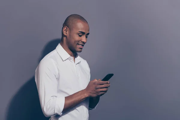 Cerrar foto de perfil lateral increíble piel oscura él su apariencia perfecta macho de las manos brazos teléfono inteligente lector de teléfonos escritura moneda corporativa desgaste camisa blanca aislado fondo gris — Foto de Stock