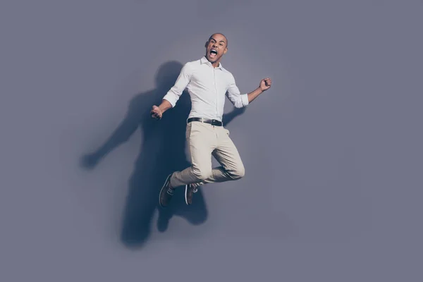 Longitud completa tamaño del cuerpo foto increíble gritando fuerte piel oscura él su macho guapo salto alto verdadero ventilador porrista fútbol béisbol baloncesto desgaste camisa blanca pantalones pastel aislado fondo gris —  Fotos de Stock