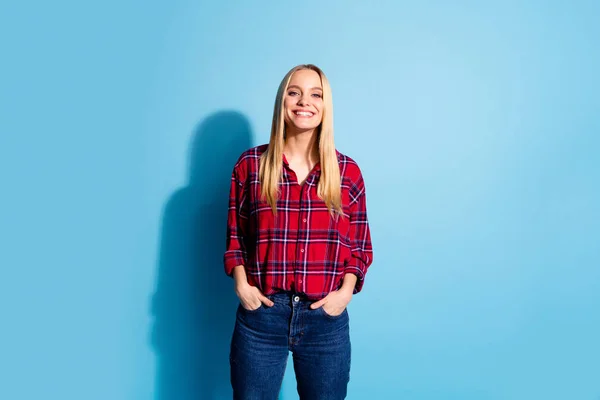 Retrato de encantadora dama guapa vestida con traje de mezclilla a cuadros lugar aislado manos palmas en los bolsillos se sienten bien sobre fondo azul — Foto de Stock