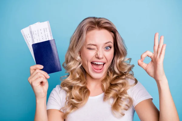 Primer plano retrato de ella ella agradable encantadora atractiva alegre optimista coqueta ondulado de pelo dama sosteniendo en la mano documentos de papel tarjeta de embarque que muestra ok-signo aislado sobre fondo pastel azul — Foto de Stock