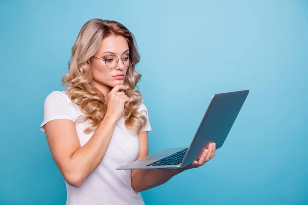 Portrait of her she nice-looking attractive focused concentrated minded wavy-haired lady in casual white t-shirt holding in hand laptop watching video isolated on blue pastel background — Stock Photo, Image