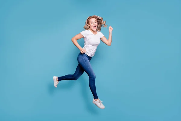 Longitud completa tamaño del cuerpo ver retrato de bonito guapo atractivo alegre alegre optimista ondulado de pelo dama en casual blanco camiseta corriendo rápido aislado sobre fondo azul — Foto de Stock