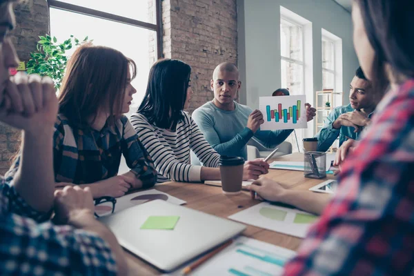 Multinacional millennial orador serio que tiene informes de seminarios documentos centrados compañeros de trabajo concentrados resolver problemas de trabajo lograr el éxito utilizando gráficos gráficos sentados en el interior alrededor de la mesa — Foto de Stock