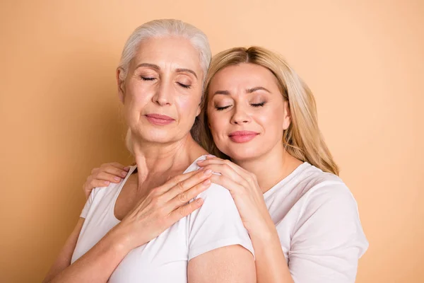 Retrato de encantadoras senhoras bonitos pessoa satisfeita mostrar confiança abraçar ondulado cacheado corte de cabelo olhos fechados daydream toque ombros descanso pacífico algodão roupas da moda isolado fundo bege — Fotografia de Stock