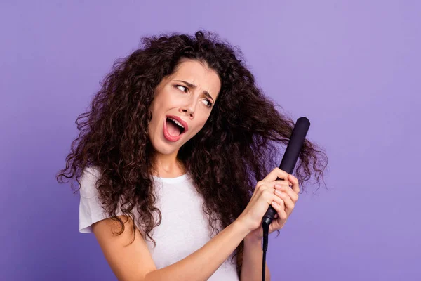 Retrato de cerca de agradable linda encantadora dama de pelo ondulado confusa atractiva usando nuevo producto eléctrico caliente planchador de alta temperatura aislado sobre brillante brillo violeta fondo pastel —  Fotos de Stock