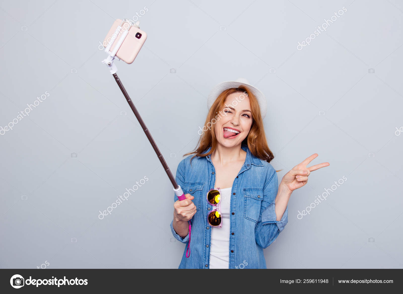 Close up photo beautiful funny funky she her lady traveler hand arm  telephone metal selfie stick blogger make pictures v-sign walk street wear  specs casual jeans denim shirt isolated grey background Stock