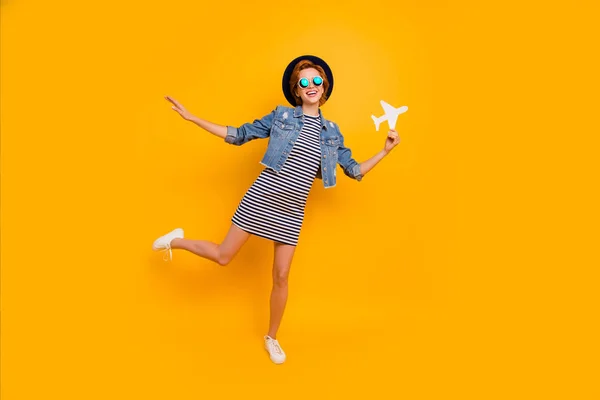 Foto lengkap ukuran tubuh foxy yang indah dia wanita kertas pesawat wisatawan bayangkan penerbangan memakai spesifikasi topi vintage garis-garis pakaian celana jeans denim kuning terisolasi latar belakang cerah cerah — Stok Foto