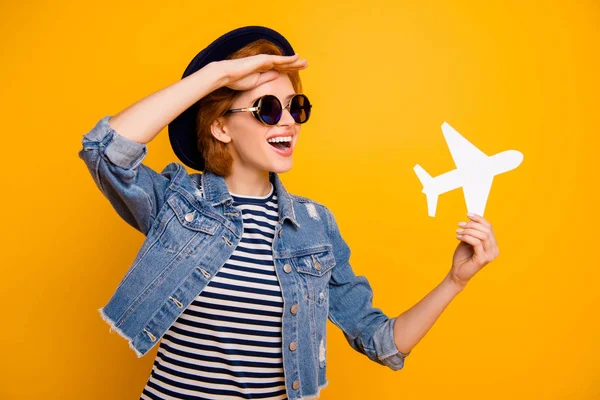 Close up photo beautiful she her lady arm hand paper airplane traveler look far away far view wear specs vintage hat casual striped t-shirt jacket jeans denim isolated yellow bright background — Foto de Stock