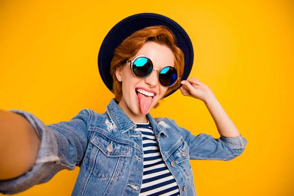 Close-up foto grappige funky Foxy ze haar Lady maken nemen selfies tong uit mond ondeugende gedrag slijtage specs Vintage Hat casual gestreepte t-shirt jas jeans denim geïsoleerd gele lichte achtergrond — Stockfoto