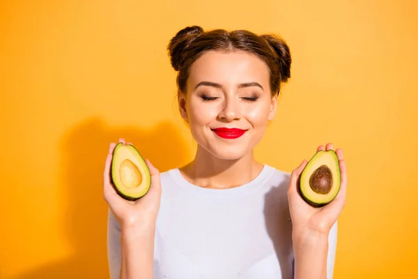 Close up foto bonita ela sua senhora muito penteado segurar duas meias fatias olhos de abacate fechado incrível procedimento de salão de beleza legal cor vermelha batom desgaste casual branco pulôver isolado fundo amarelo — Fotografia de Stock