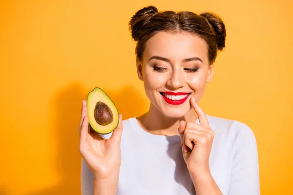 Close up photo beautiful she her her lady pretty hairdo hold slice avocado look side with interest hand arm finger chin yummy tasty wear casual white sulover clothes isolated yellow background —  Fotos de Stock