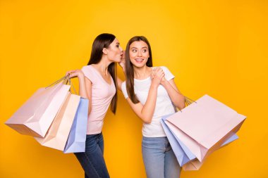 Portrait of nice cute charming winsome girlish attractive cheerful cheery straight-haired teenage girls carrying new purchase sharing secret isolated on bright vivid shine yellow background clipart