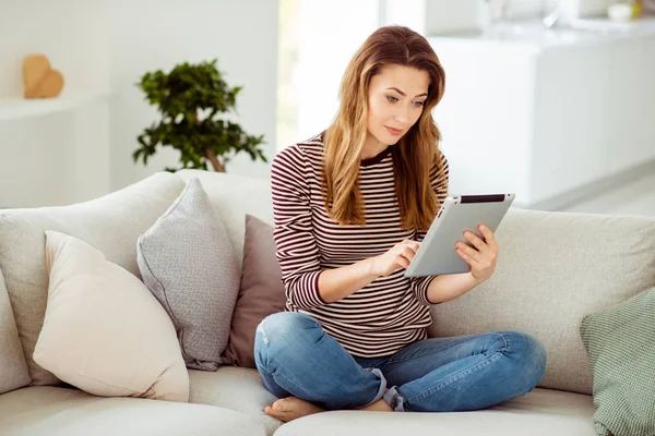 Retrato de ella ella linda linda encantadora encantadora atractiva dulce tranquila tranquila chica de pelo ondulado sentado en diván lectura libro digital en la luz blanca habitación interior — Foto de Stock