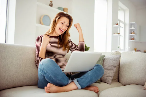 De cerca foto atractiva dama levantar puño ganó premio hermosa suerte suerte grito gritar sí ondulado rizado pelo rotura pausa sentarse diván loto posición rayas camisa denim traje bastante habitación — Foto de Stock