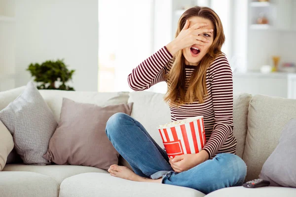 Nahaufnahme Foto schön sie ihr Modell Dame Hand Arm verbergen Gesicht schrecklich ugh Szene beängstigend Film große Container Hühneraugen tragen Jeans gestreiften Pullover Kleidung sitzen Komfort Diwan Haus Wohnzimmer drinnen — Stockfoto