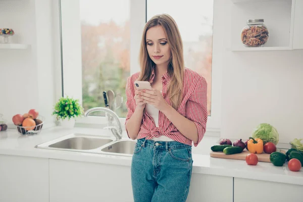 Close up photo beautiful amazing she her lady vegan hold hands arms telephone interested curious wondered homey wear domestic home apparel shirt jeans denim outfit bright flat home kitchen indoors