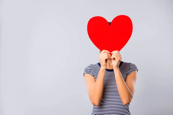 Foto close up indah menakjubkan dia wanita menyembunyikan ekspresi wajah besar kertas merah bentuk hati sosok kartu pos menebak siapa pacar permainan memakai biru putih bergaris t-shirt terisolasi latar belakang abu-abu — Stok Foto