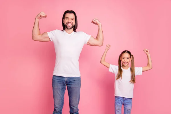 Nahaufnahme Foto schön sie ihre kleine kleine Dame er ihm seinen Papa zeigt muskulöse Hände Arme Fäuste ein Team Teamwork Gewinner tragen lässig weiße T-Shirts Jeans isoliert rosa hellen Hintergrund — Stockfoto