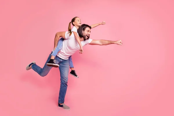 Comprimento total perfil lateral tamanho do corpo foto ela sua pequena dama ele seu pai segurar pouco princesa piggyback mãos braços pronto voar desgaste casual branco t-shirts jeans jeans isolado rosa fundo — Fotografia de Stock