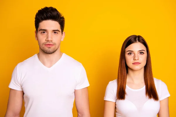 Close up photo two cool amazing beautiful she her he he him his couple standing side by side not smile look through like zombie wearing casual white t-shirts outfit clothes isolated yellow background — Stockfoto