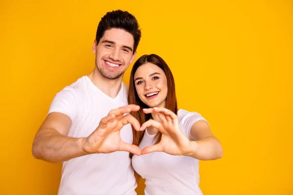 Close up foto incrível linda ela ele ele seu cara senhora mãos braços dedos fazer figura do coração forma romance humor abraçando sincero desgaste casual branco t-shirts roupa isolado fundo amarelo — Fotografia de Stock