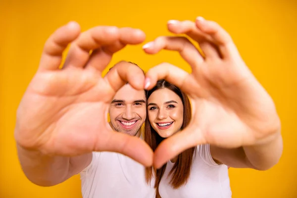 Close up photo amazing she her he him his guy lady hands arms fingers make heart figure faces inside form married spouse romance mood wear casual white t-shirts outfit isolated yellow background — Stock Photo, Image