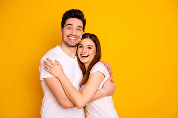 Close up photo beautiful amazing she he he he he his guy lady pair holding hands arms toothy best emotions in love abrazos stand close sweetheart wear casual white t-shirts isolated yellow background — Foto de Stock
