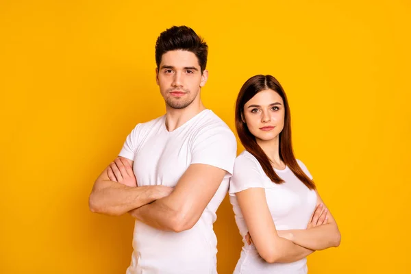 Close up photo beautiful she her he him his pair stand back close teamwork self-confident not smiling professionals specialists work job workers wear casual white t-shirts isolated yellow background — Stock Photo, Image