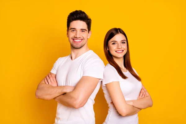 Close up photo beautiful she her he him his pair stand back side close teamwork self-confident professionals specialists work job reliable workers wear casual white t-shirts isolated yellow background — Stock Photo, Image