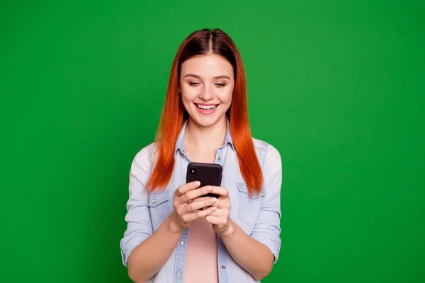 Ritratto di interessato ispirato grazioso adolescente isolato uso utente dispositivo blog blogger ricerca informazioni leggere soddisfatto contenuto capelli lunghi abito denim dritto su sfondo verde — Foto Stock