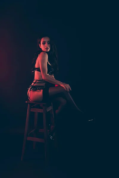 Vertical of nice lovely magnificent delicate attractive fit thin wavy-haired lady wearing swordbelt sitting on chair bar stool isolated over red light black background — Stock Photo, Image