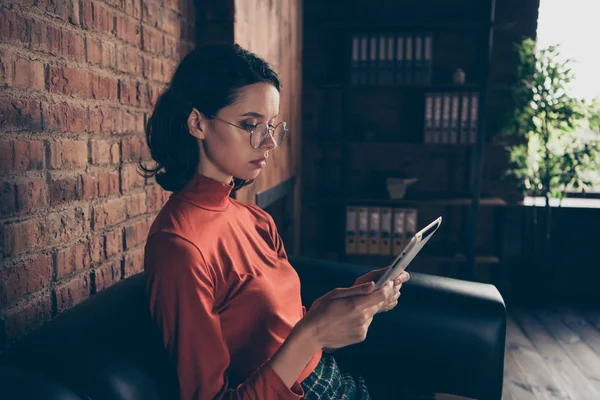 Profile side view photo serious concentrated assistant hold hand device search information do analysis sit sofa eyeglass trendy style stylish red sweater skirt brunette beautiful industrial free time — Stock Photo, Image
