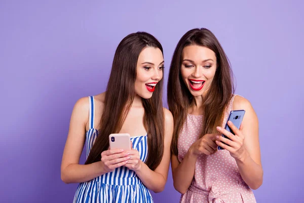 Yakın fotoğraf iki kişi güzel o onun modelleri bayanlar telefon akıllı telefon yenilik gösteren kullanarak instagram takipçileri resimleri renkli elbiseler izole mor mor arka plan giymek — Stok fotoğraf