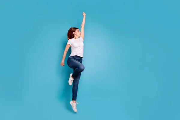 Pleine longueur profil taille du corps vue de côté portrait de belle fille forte gaie attrayante en t-shirt blanc mode de vie d'humeur active levant le bras vers le haut isolé sur fond bleu brillant vif — Photo