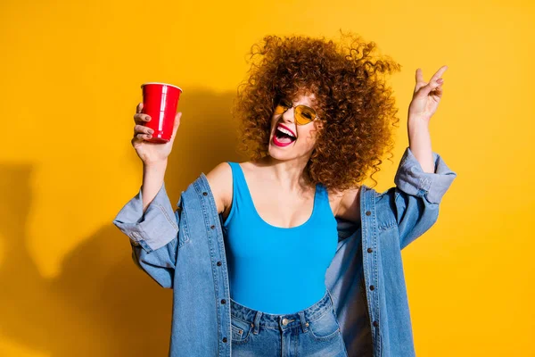 Close up photo beautiful she her lady wavy styling curls festive mood dance dancer clubber beverage hand wear specs casual jeans denim shirt shorts tank top outfit clothes isolated yellow background — Stock Photo, Image