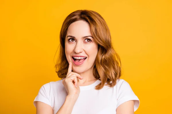 Close up photo beautiful amazing she her pretty lady arm hand finger chin look wondered up empty space tricky toothy cute minded wear casual white t-shirt isolated yellow bright background — Stock Photo, Image