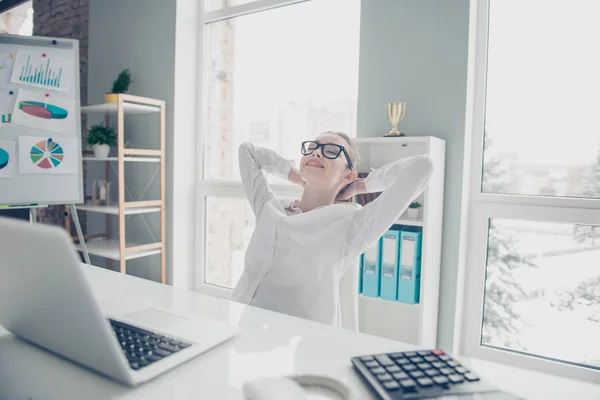 Close up photo beautiful she her business lady hands behind head after business start up eyes closed toothy eyewear occhiali notebook table sit bright office wear specs formal-wear white shirt — Foto Stock