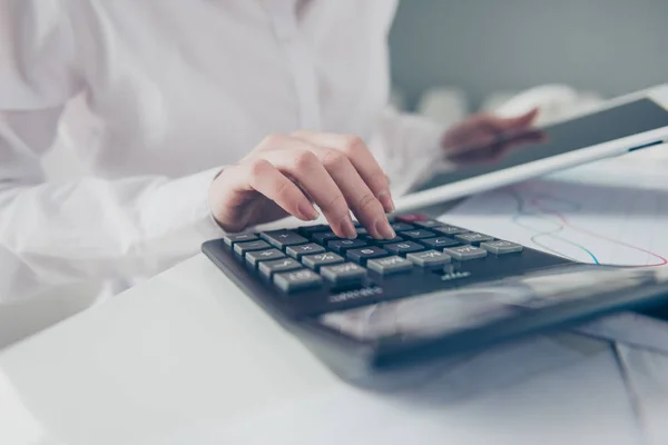 Foto yang dipotong dari dekat indah dia wanita bisnisnya menghitung gaji freelance menghitung pendapatan investasi menahan jam tangan membandingkan tangan data buku catatan e-reader meja mengenakan formal-memakai kantor cerah — Stok Foto