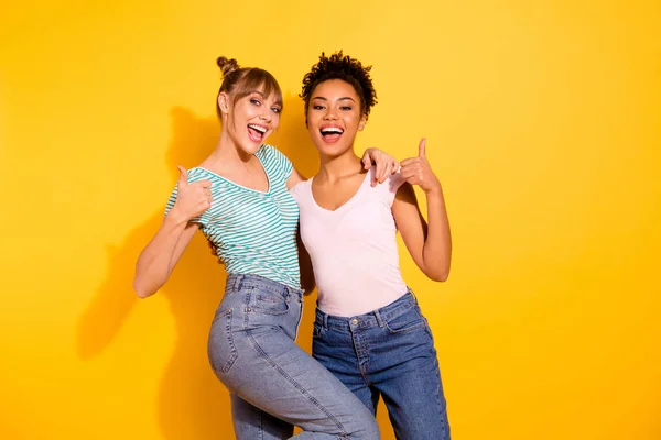 Close-up foto funky mooi ze haar Lady knuffel omarmen knuffelen houden duim verheven omhoog symbool verschillende vrienden ja goedkeuring slijtage casual wit gestreepte t-shirt outfit geïsoleerd gele lichte achtergrond — Stockfoto