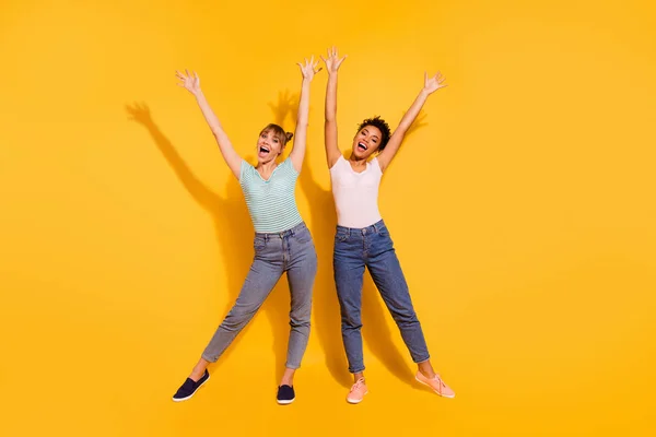 Full längd kroppsstorlek foto vacker hon hennes dam fritid gläd kompisar Fellows olika nationaliteter händer armar upphöjd slitage casual vit randig t-shirt kläder isolerad gul ljus bakgrund — Stockfoto