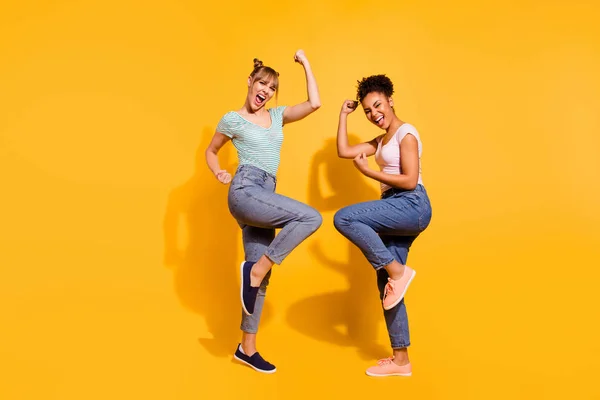 Volledige lengte zijkant profiel lichaam grootte foto mooie winnaars ze haar dame verschillende nationaliteiten handen armen vuisten wild Yell slijtage casual wit gestreepte t-shirt kleren geïsoleerd gele lichte achtergrond — Stockfoto