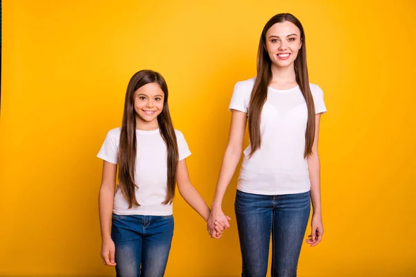 Närbild foto två vackra henne hon mångfald dam olika ålder bästa kompisar hålla händerna armar gå sekundär highschool slitage casual vit t-shirts Jeans denim kläder isolerad gul ljus bakgrund — Stockfoto