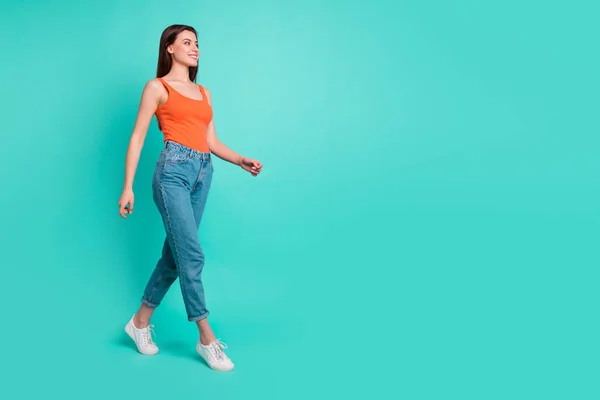 Full length side profile body size photo beautiful her she lady wondered look empty space weekend walking park wear casual orange tank-top jeans denim isolated bright teal turquoise background