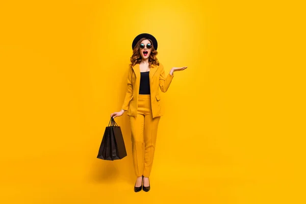 Teljes hosszúságú test mérete fotó szép őrült lány hölgy szállítására nyitott tenyér ruha csomag tökéletes megjelenés új, alacsony ár értékesítés kedvezmény kopás szemüveg formális-Wear jelmez öltöny elszigetelt sárga fényes háttér — Stock Fotó