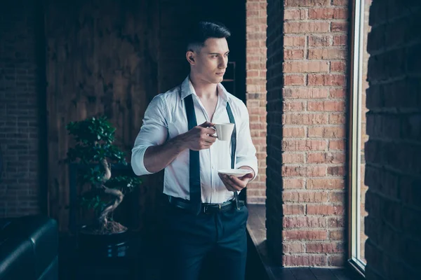 Close up photo handsome amazing he him his wondered hands arms hold hot beverage look window dream dreamy imaginary flight wear formal-wear dress code shirt stand indoors modern office place — Stock Photo, Image