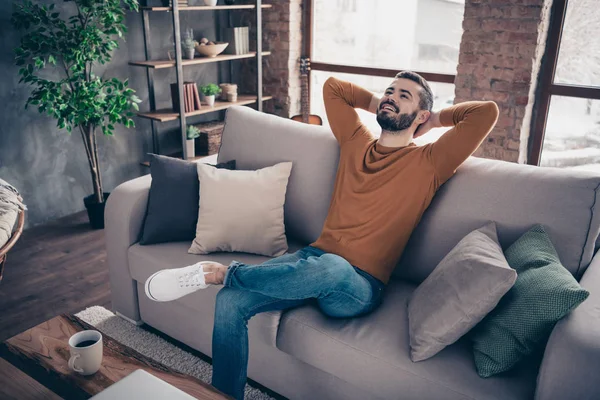 Retrato de su agradable atractivo barbudo alegre alegre contento chico sentado en diván tener descanso en el interior loft industrial de madera ladrillo estilo sala de estar en el interior — Foto de Stock