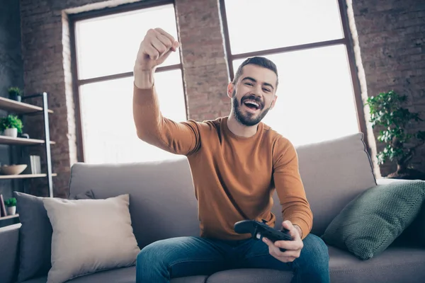Porträt seines hübsch aussehenden attraktiven bärtigen fröhlichen fröhlichen fröhlichen Kerls, der das Wochenende auf dem Sofa verbringt und die Xbox-Unterhaltung im industriellen Loft-Backstein-Wohnzimmer drinnen gewinnt — Stockfoto